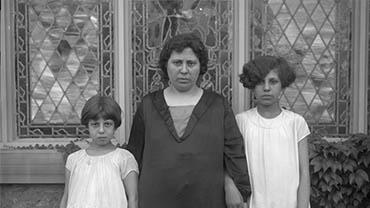 A woman and two children stand in front of a stained glass window